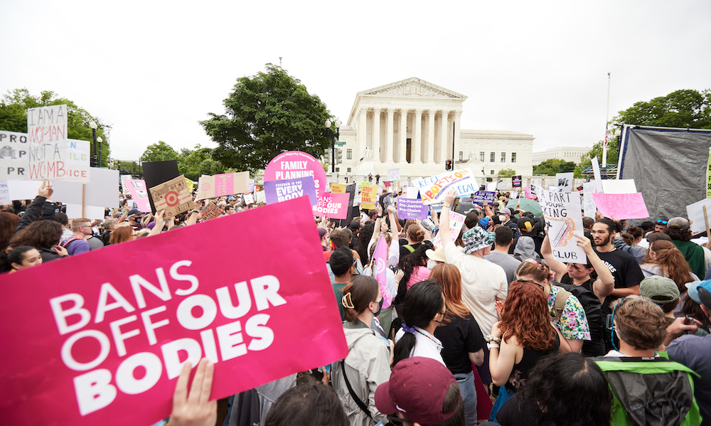 A reproductive rights rally outside of the Supreme Court with a sign in the foreground saying, "Bans Off Our Bodies."